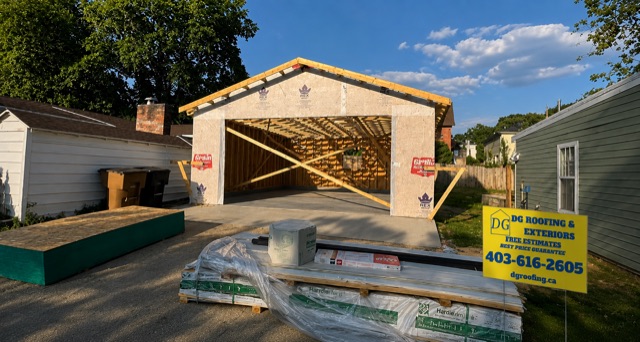 Detached garage framed and sheathed, materials stacked out front