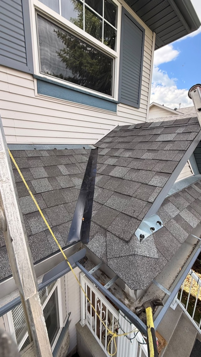 Shingles going on a small roof section beside a ladder