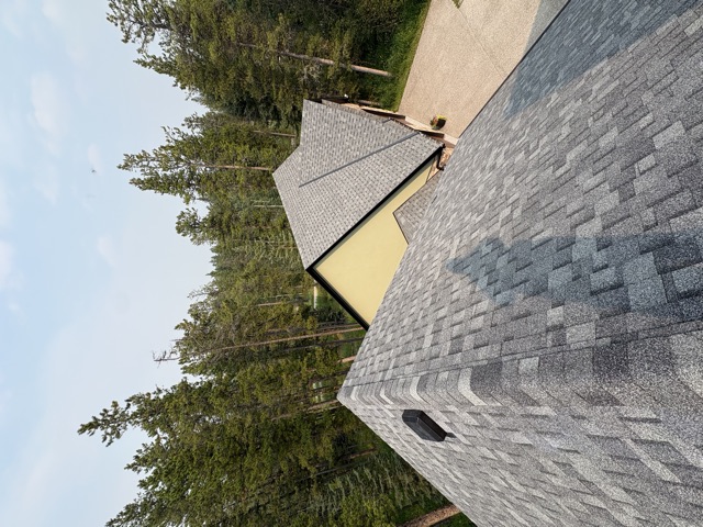 Shingle roof, spruce trees and a valley beyond