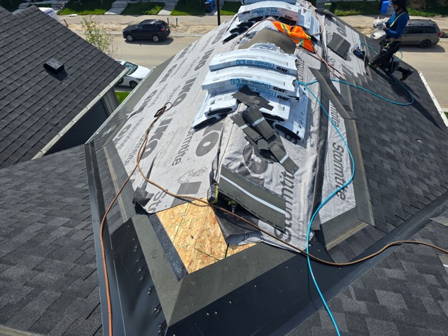 Underlayment and shingle bundles on a roof, crew at work