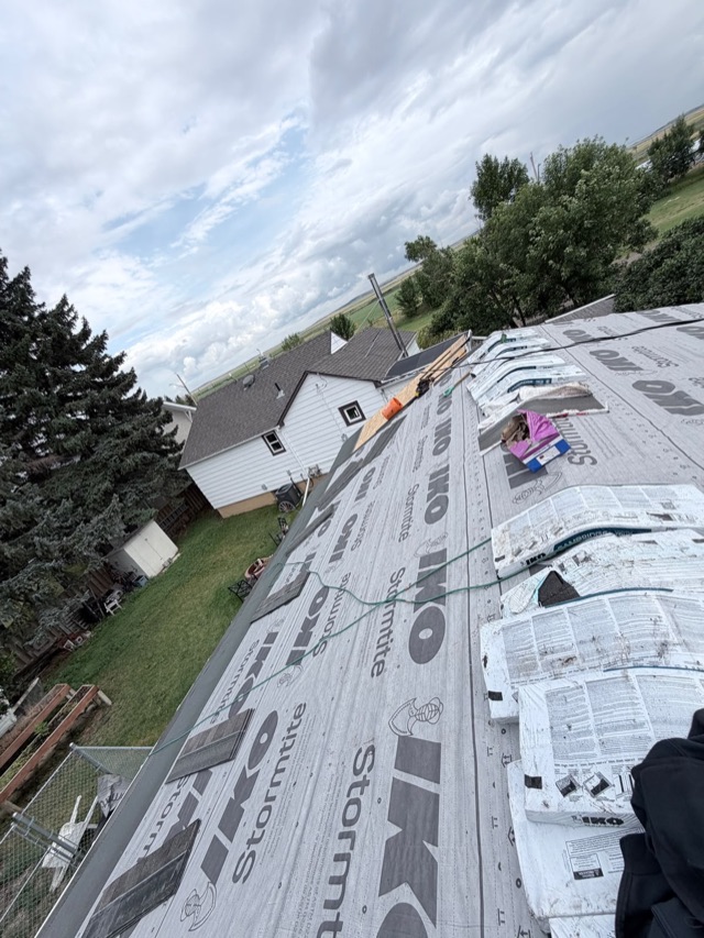 Hip roof mid-job, underlayment down and bundles staged