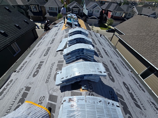 Underlayment down along a ridge, bundles staged