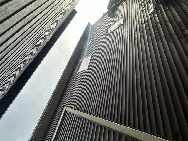 Dark brown siding on a two-storey wall