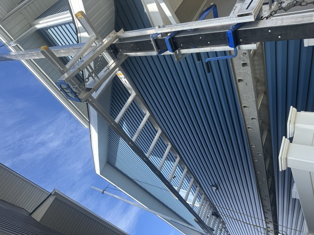 Navy siding going on a two-storey wall, ladder hoist in place