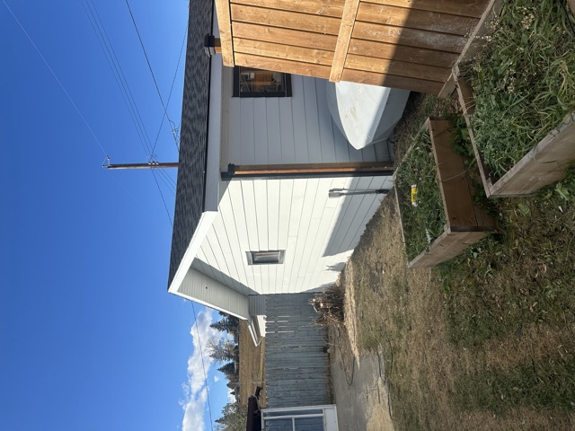 White siding on a small building beside a wood gate