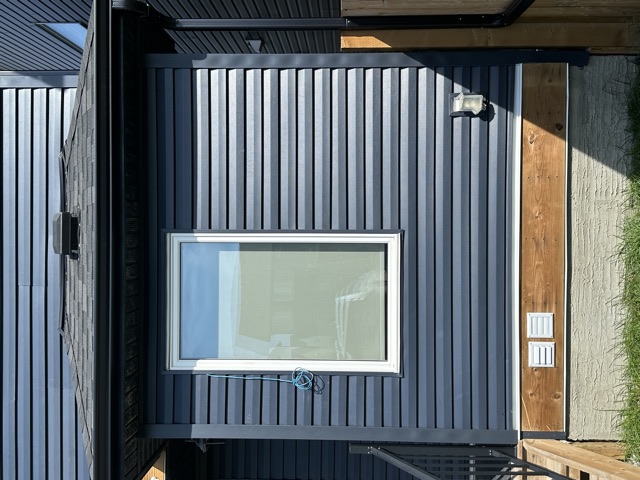 Navy siding trimmed around a white window